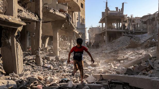 Ein Kind geht durch Ruinen in Gaza
