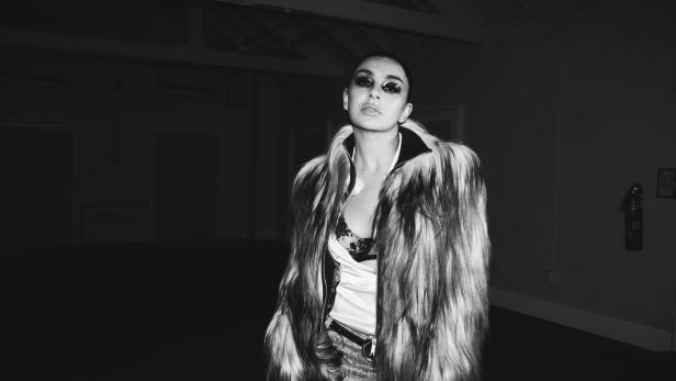 Die Musikerin Charli xcx in eienm schwarzweißen Foto, mit Sonnenbrillen und Pelzjacke