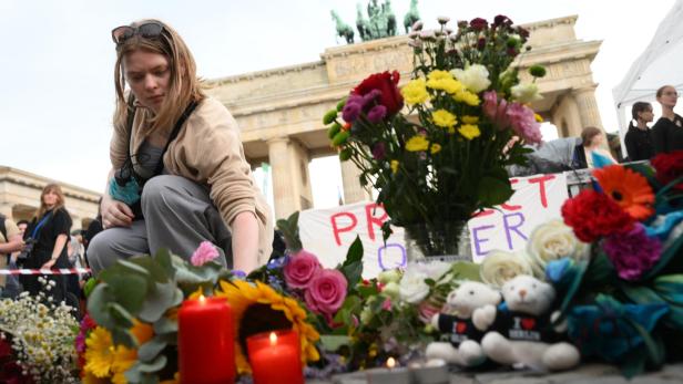 Eine trauernde Frau legt Blumen beim Brandenburger Tor ab.