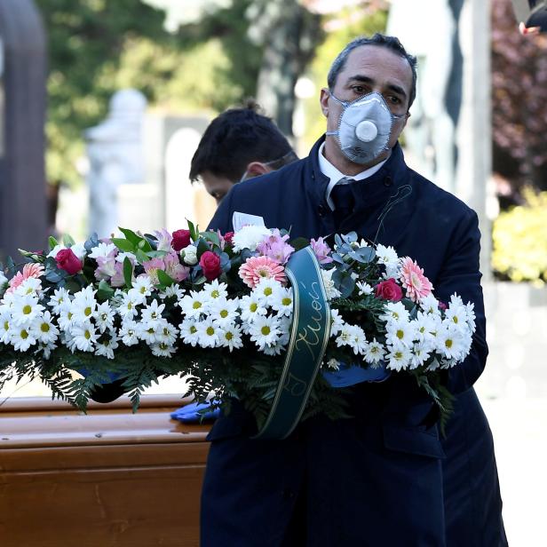 FILE PHOTO: Cemetery workers and funeral agency workers in protective masks transport a coffin of a person who died from coronavirus disease (COVID-19), into a cemetery in Bergamo