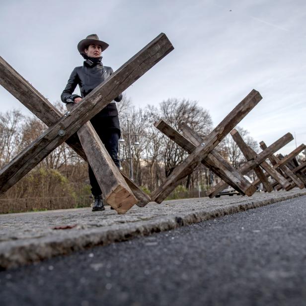 Die Künstlerin Dafne B zwischen ihrer Installation aus 50 hölzernen Panzersperren in Berlin. Mit der Kunstinstallation am Tag der Menschenrechte will die Künstlerin das Thema der inneren Blockade aufgreifen.