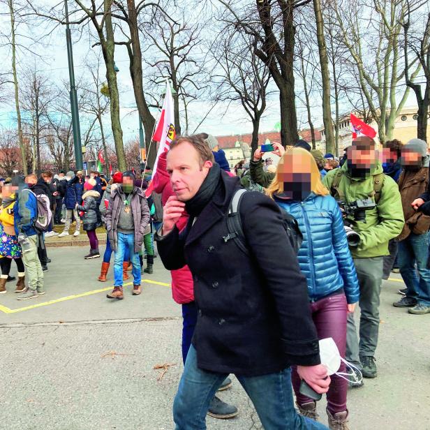 Eine Menschenmenge demonstriert auf einer Straße, im Hintergrund Polizisten.