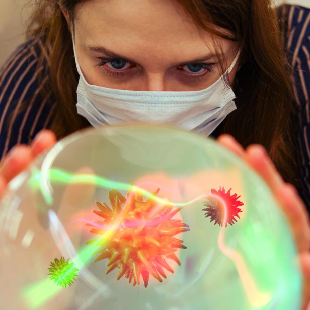 Eine Frau sieht in eine Glaskugel mit einem Virus.