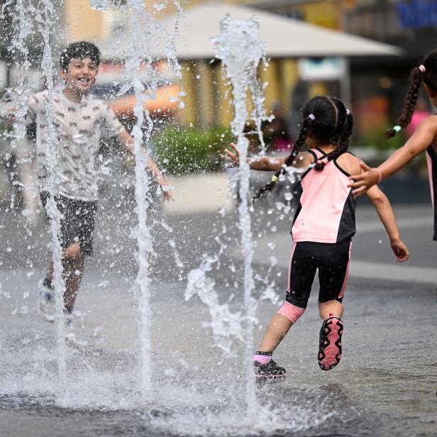 Kinder kühlen sich ein Wasserfontänen in einer Fußgängerzone in Wien