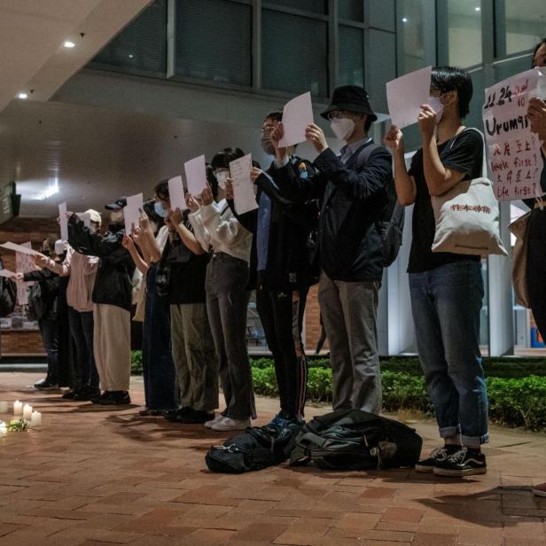 Demonstranten halten ein Schild und ein leeres Blatt Papier auf dem Campus der Universität Hongkong in Solidarität mit den Demonstrationen in Festlandchina gegen strenge Covid-Beschränkungen und für mehr Freiheiten fordern, in Hongkong, am 29. November 2022.