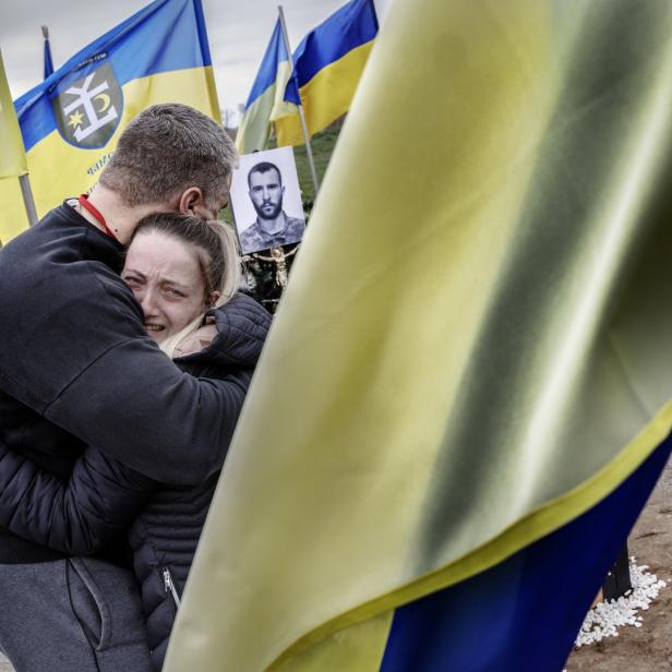 Rot Kreuz-Helfer Sergej umarmt die 23-jährige Dima am Friedhof in Homostel