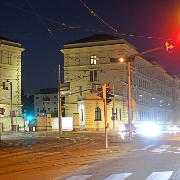 Eine nächtliche Straßenszene in einer Stadt mit beleuchteten Gebäuden und Ampeln.