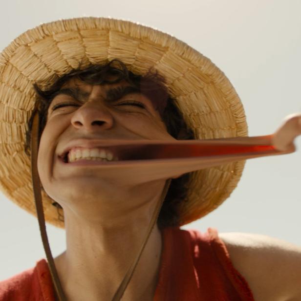Ein Mann mit Strohhut dehnt sein Gesicht, vermutlich eine Darstellung von Monkey D. Luffy.
