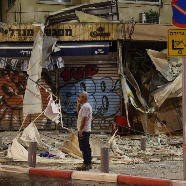 A man stands in front of a damaged shop in Tel Aviv, after it was hit by a rocket fired by Palestinian militants from the Gaza Strip on October 7, 2023. Palestinian militant group Hamas launched a surprise large-scale attack against Israel on October 7, firing thousands of rockets from Gaza and sending fighters to kill or abduct people as Israel retaliated with devastating air strikes. JACK GUEZ / AFP