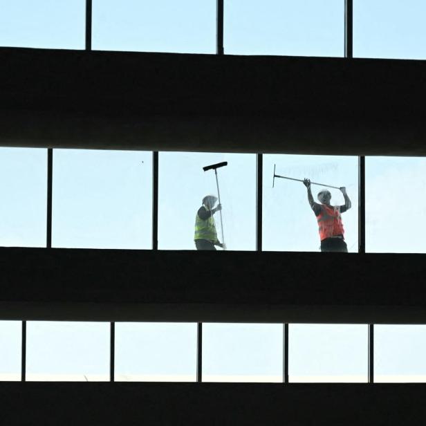 Indische Arbeiter auf einem Dach die Fenster reinigen.