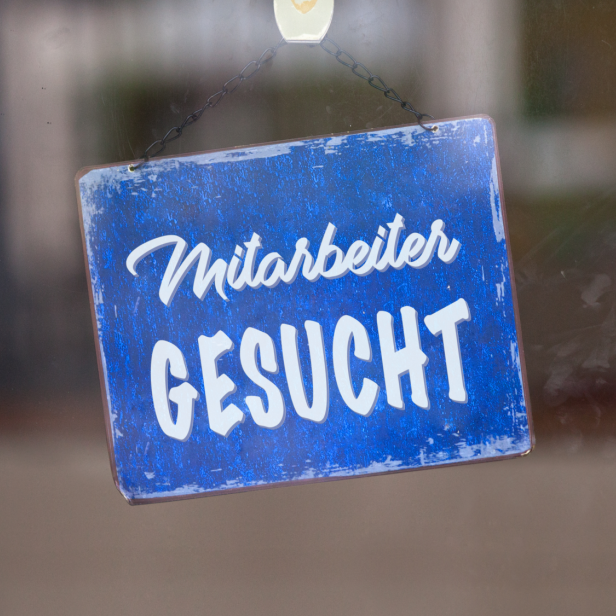 Im Schaufenster hängt ein Schild "Mitarbeiter gesucht"