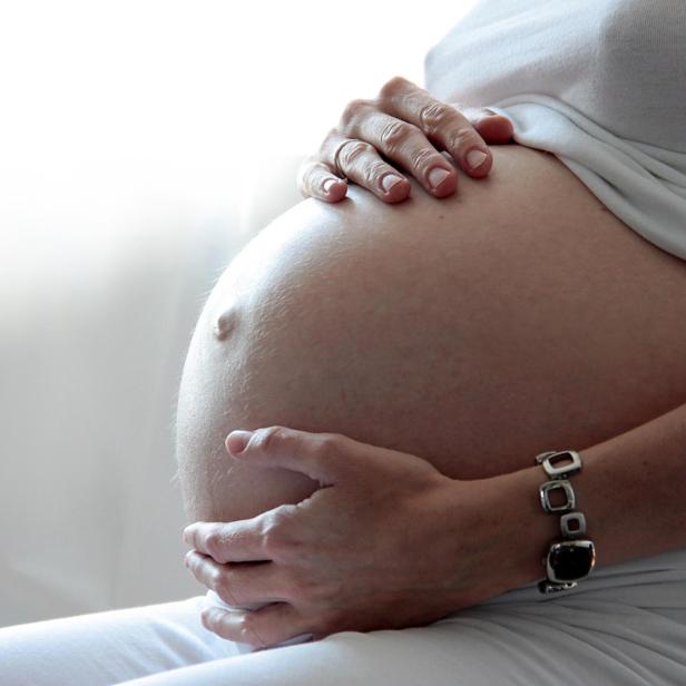 Eine Frau hält ihren schwangeren Bauch.