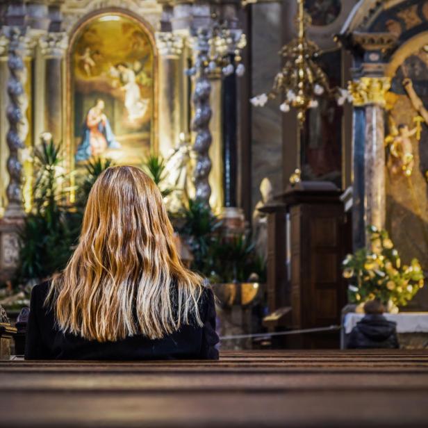 Junge Frau sitzt allein in der Kirche.