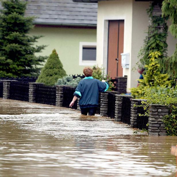 Eine Frau steht 2002 in Schwertberg bis zu den Oberschenkeln im Wasser vor ihrem Haus.