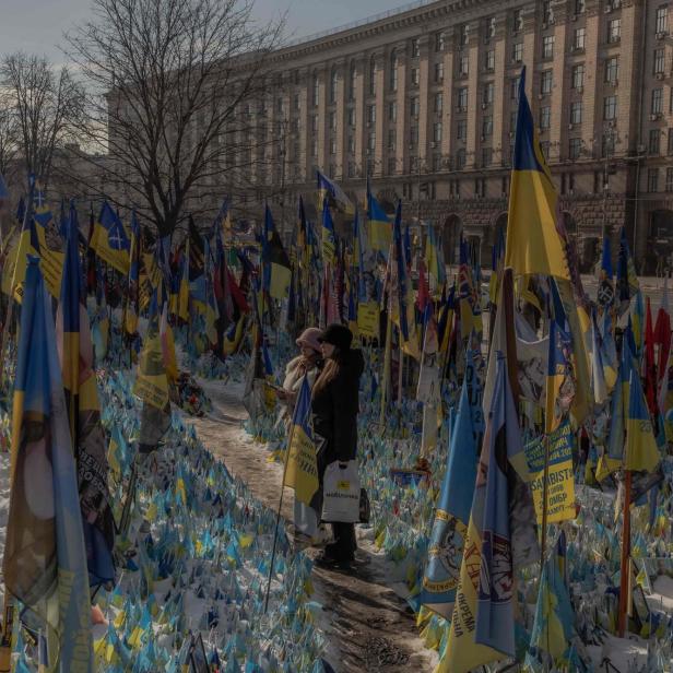 Am 23. Februar 2025, vor dem dritten Jahrestag der russischen Invasion in der Ukraine, stehen Besucher neben einem provisorischen Denkmal, das ukrainische und ausländische Kämpfer mit Fahnen auf dem Unabhängigkeitsplatz in Kiew würdigt.