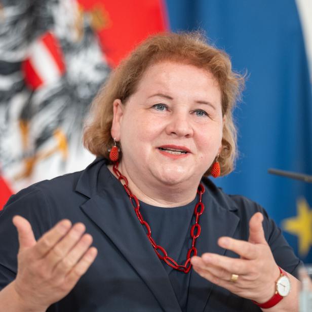Sozialministerin Korinna Schumann bei einer Pressekonferenz im Bundeskanzleramt vor einer Fahne von Österreich und der EU 