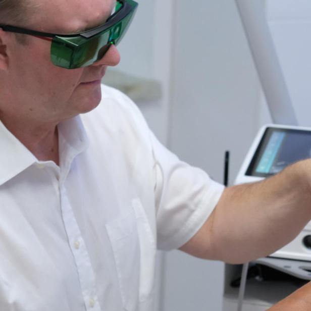 Ein Mann macht eine Lasertherapie. 