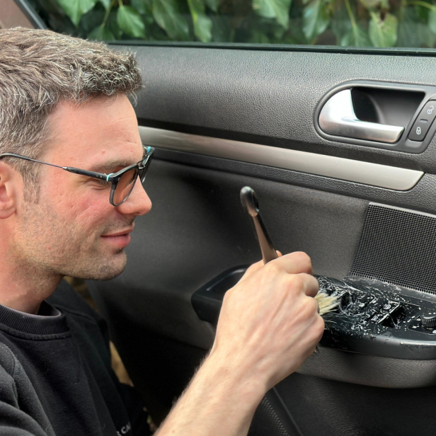 Ein Mann kümmert sich um ein Auto. 