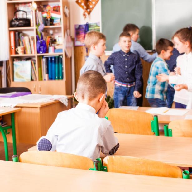 Junge sitzt einsam in Klassenzimmer