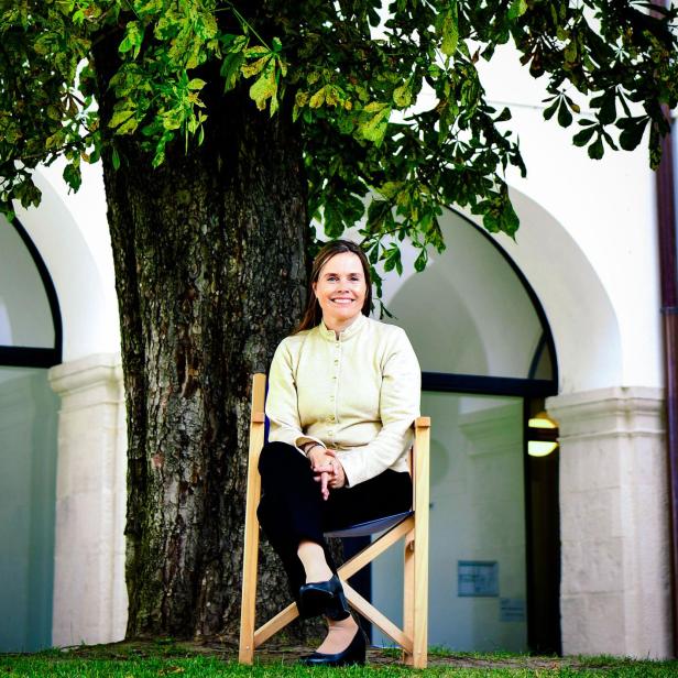 Katrín Jakobsdóttir sitzt vor einem Baum im Campus der Akademie der Wissenschaften, Wien.