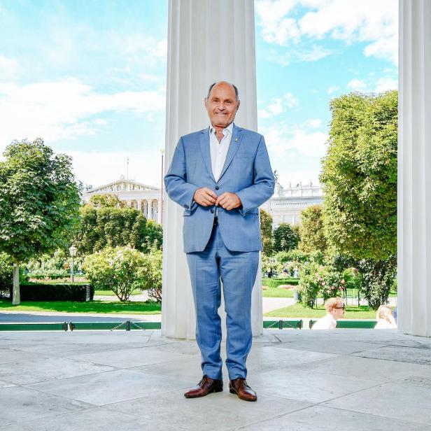 Wolfgang Sobotka steht im blauen Anzug im Wiener Volksgarten, hinter ihm ist das Parlament zu sehen