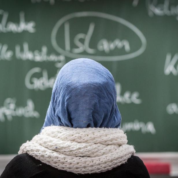 Man sieht eine Schülerin mit Kopftuch vor einer Tafel