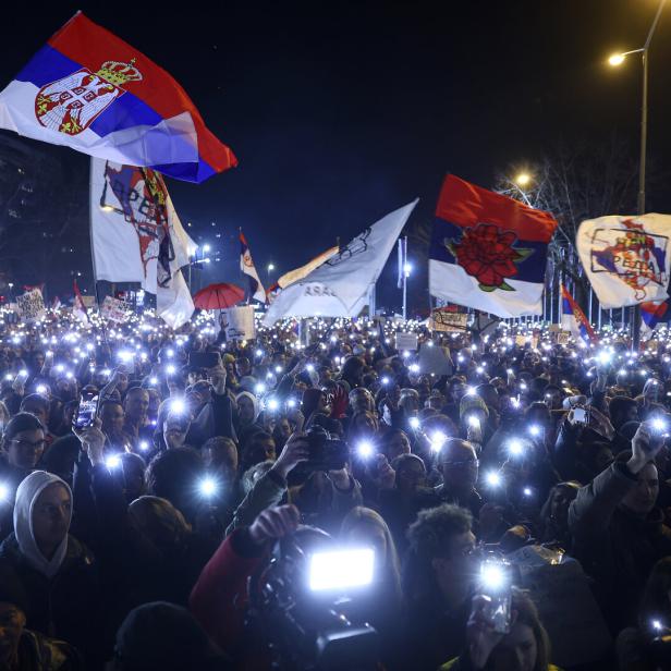 Demonstrierende halten bei einem Protest ihre erleuchteten Smartphones hoch. 