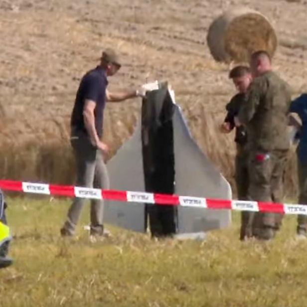 Sicherheitsleute betrachten eine Drohne, die über einem Feld abgestürzt ist