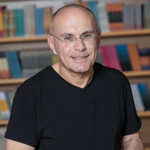 Porträtfoto von Yagil Levy. Es zeigt einen lächelnden Mann in schwarzen Shirt mit Brille.