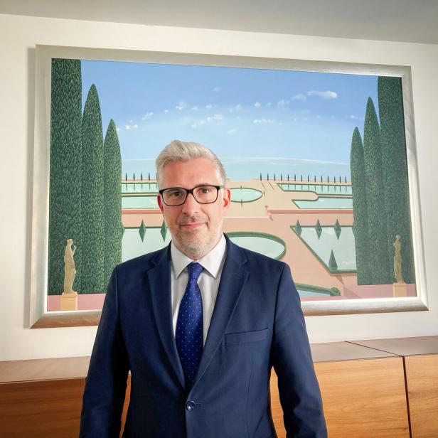 Marko Štucin steht in einem blauen Anzug vor einem Bild 