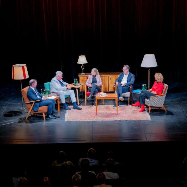Vom links nach rechts:Gernot Bauer, Andreas Mölzer, Anna Thalhammer, Heinz Christian Strache und Eva Linsinger sitzen auf der Bühne des Theater Akzent. Um sie herum sind Stehlampen plaziert. Der Hintergrund ist dunkel. Am Fuße der Bühne sind die Köpfe der Zuschauer auszumachen.