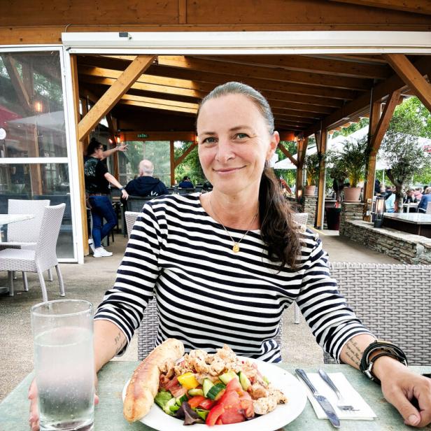 Katharina Nehammer sitzt an einem Tisch, vor sich ein Salat.