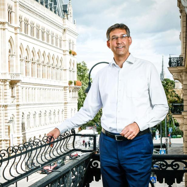 Ein Mann im weißen Hemd steht lächelnd auf einem Balkon. Es handelt sich um den Chef der Wiener ÖVP, Markus Figl. Daneben ist die Fassade des Wiener Rathauses zu sehen.