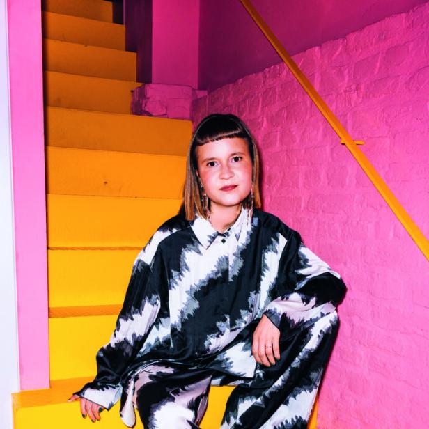 Junge Frau sitzt auf gelber Treppe