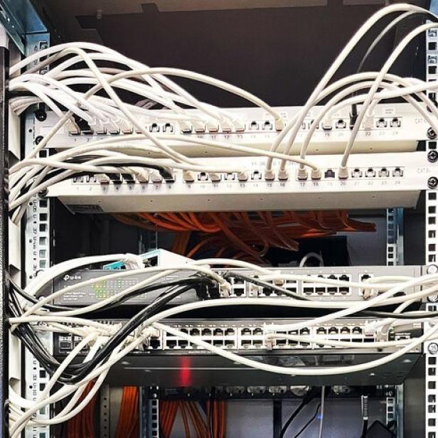 Die Internetquelle von Karosserie Puck. Viele weiße und schwarze Kabel winden sich durch das Bild und verbinden mehrere Internet-Router-Boxen.