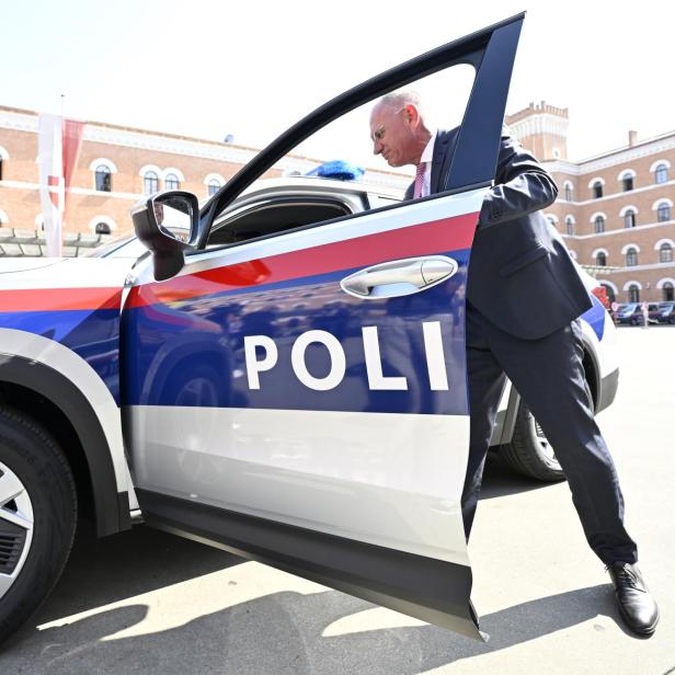 auf dem Bild ist Innenminister Gerhard Karner (ÖVP) beim Inspizieren eines Polizeiautos zu sehen