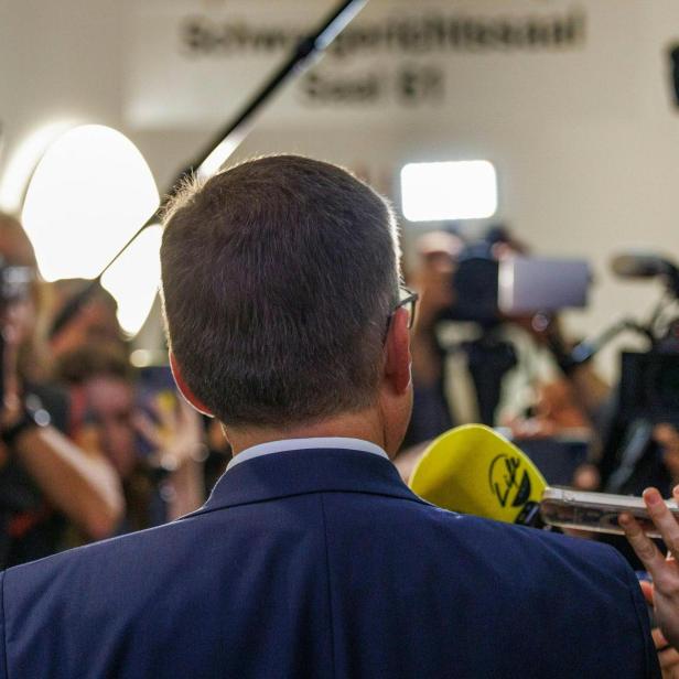 August Wöginger ist von hinten zu sehen, vor ihm stehen Reporter mit Kameras und Mikrofonen.