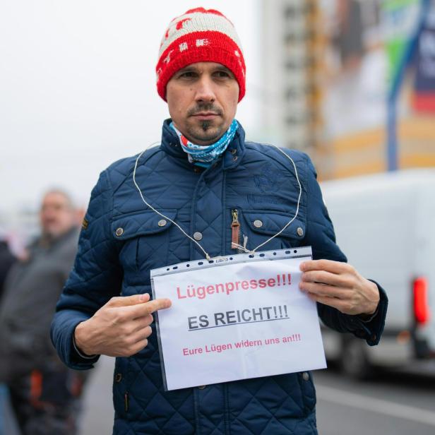 Verschwörungstheoretiker Martin Rutter mit roter Mütze hält Schild mit der Aufschrift „Lügenpresse!!! ES REICHT!!!“.