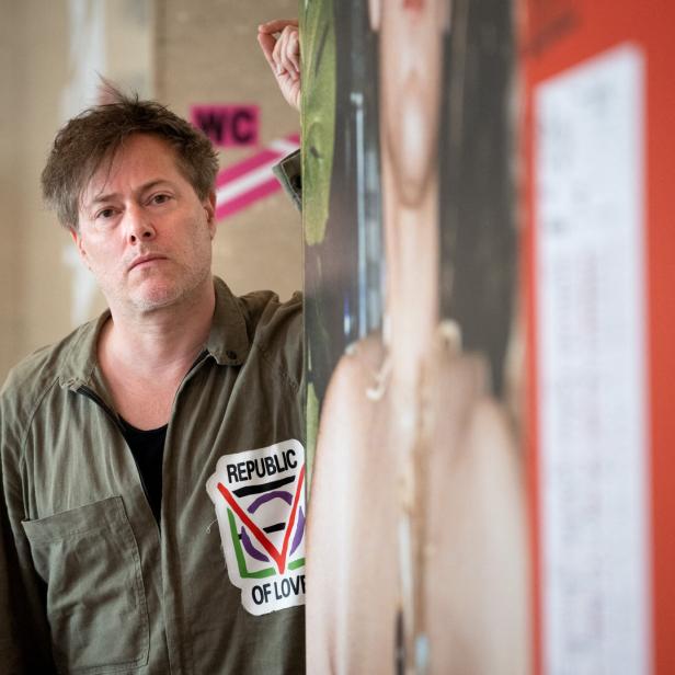 Mann im grüne Overall schaut hinter einer Büroecke hervor