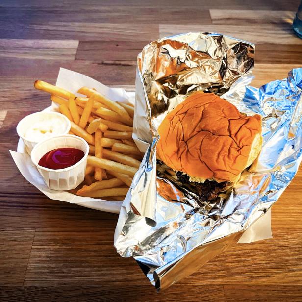 Das Bild zeigt einen Smashburger mit Pommes, Ketchup und Mayonnaise