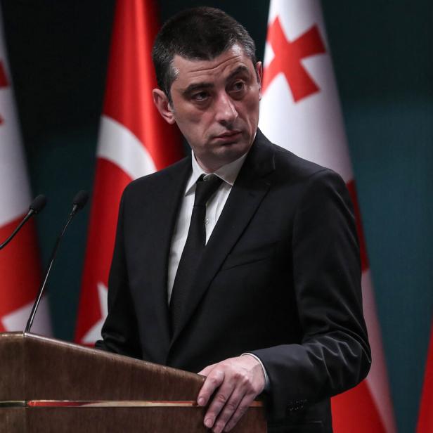 Ein Mann in Anzug (Giorgi Gacharia) spricht vor einem Podium, dahinter Türkei- und Georgien-Flaggen.
