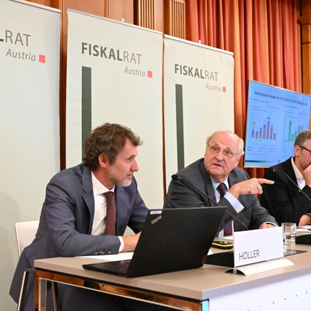 Die Vertreter des Fiskalrats, in der Mitte Präsident des Fiskalrates Christoph Badelt, sitzen nebeneinander bei der Pressekonferenz. Hinter ihnen sind drei Banner mit dem Fiskalrats-Logo.