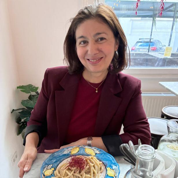 Jetzt-Chefredakteurin Hatice Akyün sitzt an einem Tisch vor einem Teller Spaghetti und lächelt in die Kamera