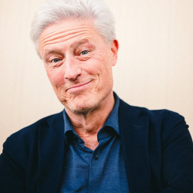 Kabarettist Florian Scheuba, in Hemd und Sakko, lächelt in die Kamera