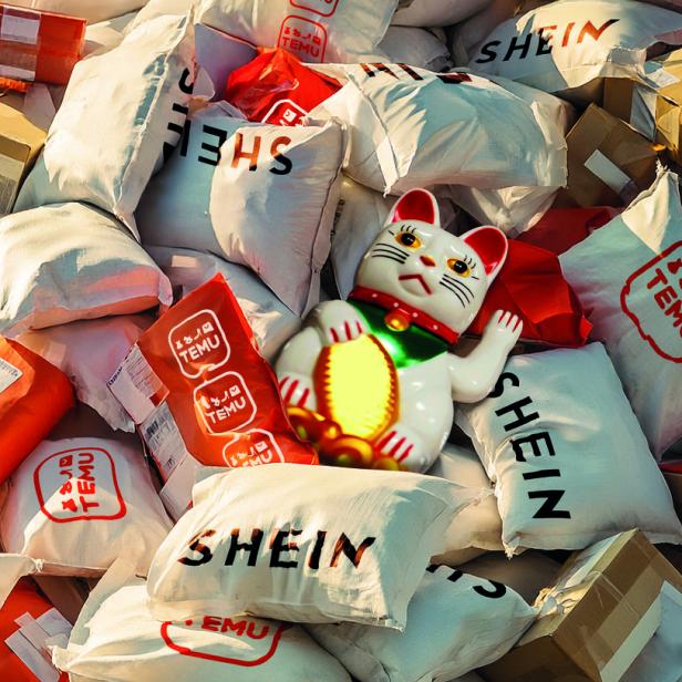 Ein Haufen Plastikbeutel von Shein und Temu, dazwischen liegt eine chinesische Winkekatze.