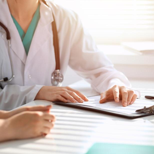 Das Bild zeigt eine praktische Ärzten im Diagnosegespräch.