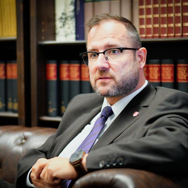 Christian Hafenecker sitzt auf einer Couch vor einem Bücherregal