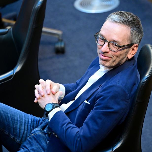 Ein Mann mit Brille und blauer Jacke, FPÖ-Obmann Kickl, sitzt entspannt auf einem Stuhl und verschränkt die Hände.
