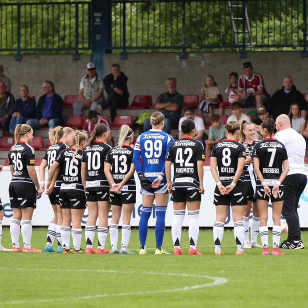 Spielerinnen des LASK stehen auf einem Fußballplatz und sind von hinten zu sehen