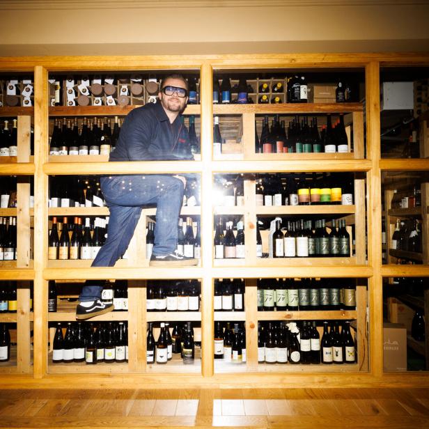 Zu sehen ist der Sommelier Willi Schlögl, der auf einem Weinregal herumklettert